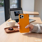 digitaley.co orange phone case with miniature Turkish coffee cup and chocolate charm, held by a person at a cafe table.