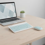 digitaley.co pastel blue wireless keyboard and mouse set with quiet keys on a wooden desk next to a laptop.