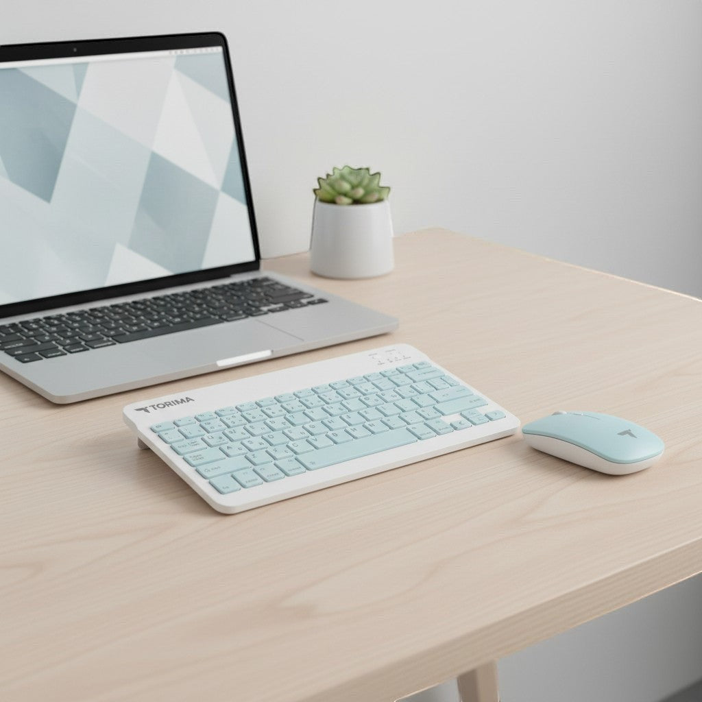 digitaley.co pastel blue wireless keyboard and mouse set with quiet keys on a wooden desk next to a laptop.